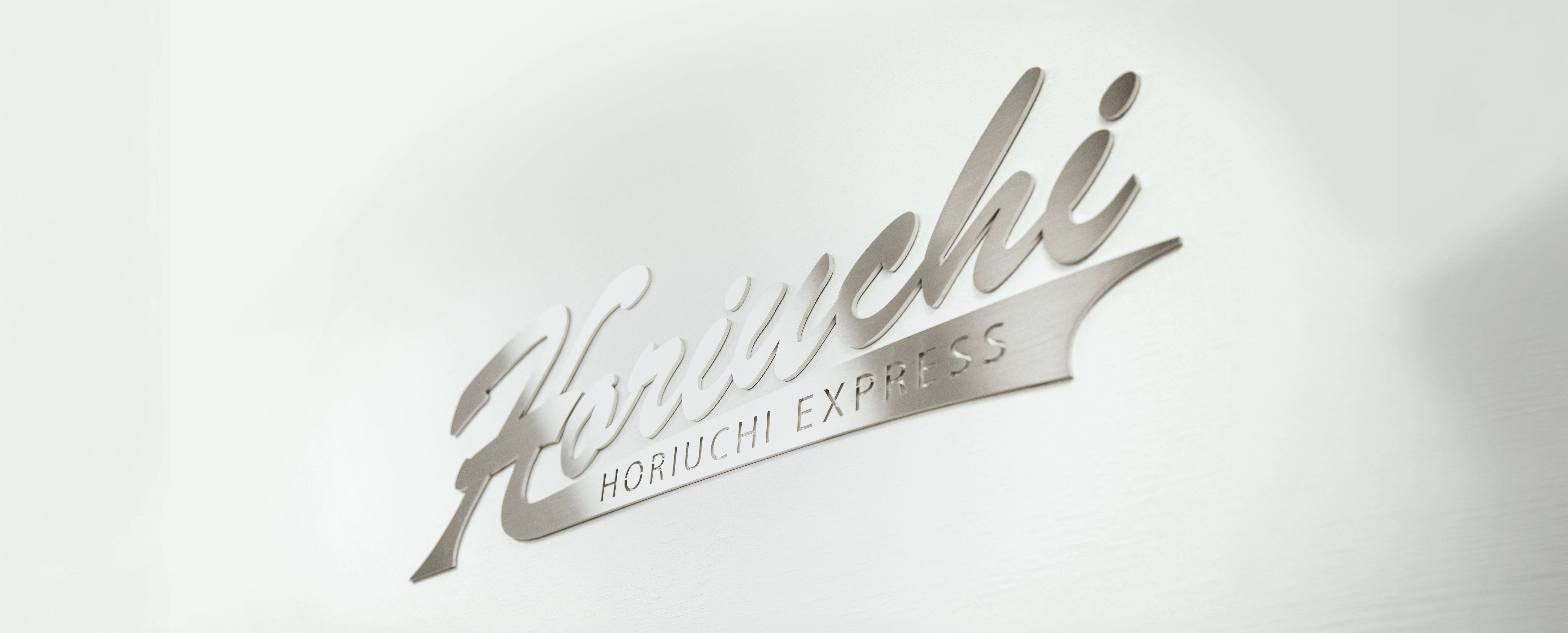 壁面に設置されたHoriuchi EXPRESSのシルバーロゴ